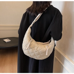 Detail of beige quilted crescent shoulder bag showing diamond stitch fabric and texture