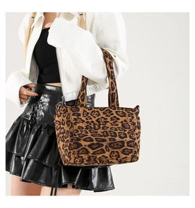 Detail of leopard print canvas tote bag featuring double handles and side metal hardware