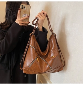 Detail showing the brown PU leather texture and stylish metal zippers on a handbag