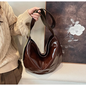 Detail of dark brown glossy PU leather hobo bag with gold adjustable metal buckle strap