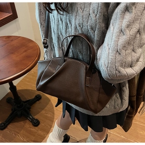 Detail of dark brown pleated PU leather handbag with adjustable shoulder strap and matte finish