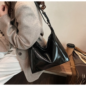 Sac fourre-tout noir en similicuir brillant avec bandoulière réglable en situation