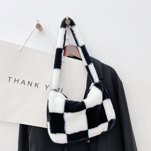 Close-up of black and white checkered plush shoulder bag on a wooden hook in a modern setup