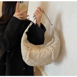 Detail of beige quilted hobo bag with woven zipper pull and adjustable strap