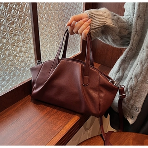 Detail of burgundy PU leather handbag featuring pleated texture and silver hardware