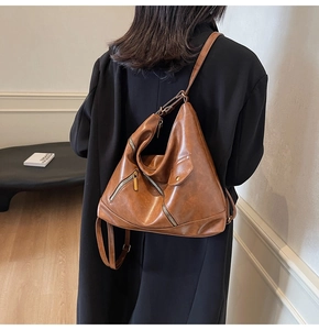 Detailed view of the brown PU leather shoulder bag with metallic zippers on a model