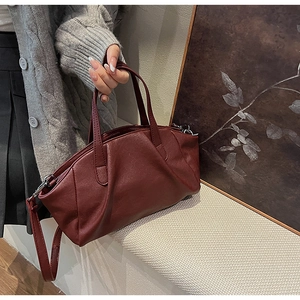 Detail of burgundy PU leather crossbody bag with pleated texture and silver hardware