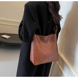 Detail of vintage brown leather tote bag showing side metal buckle and wrinkled texture
