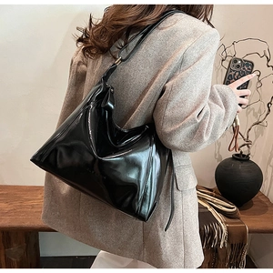 Grand cabas en cuir verni noir porté avec un blazer en laine gris pour un look chic