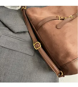 Detail eines verstellbaren braunen Schultergurts mit Gold-Schnalle an Wildleder-Tasche