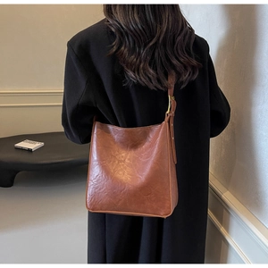 Side view of a vintage brown tote bag showing adjustable strap and golden hardware on model