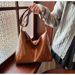 Détail du sac bandoulière en cuir PU marron caramel avec une silhouette Hobo souple