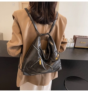 Detail of a black PU leather backpack with diagonal zippers and small flap pocket