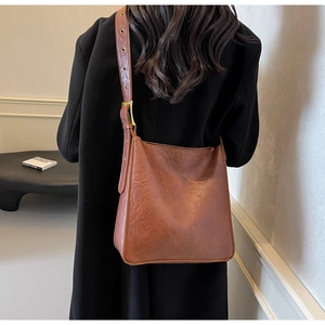 Brown vintage tote bag in retro faux leather styled as a shoulder bag on a black coat