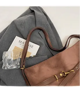 Detailansicht der braunen Wildledertasche mit robusten Ledergriffen und Goldmetallschnallen