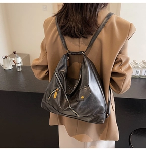 Detail of the black geometric PU leather backpack with gold zipper on a model in a cafe