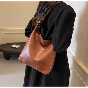 Close-up of brown vintage PU leather tote bag with elegant gold metal strap buckles