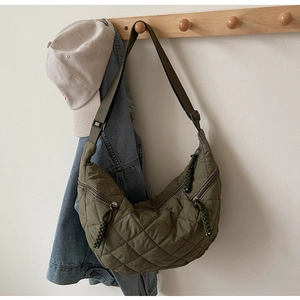 Quilted emerald green crescent shoulder bag with minimalist diamond pattern and woven zipper pull