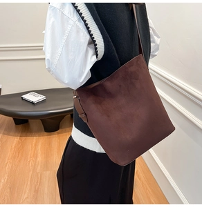 Detail view of adjustable buckle on dark brown suede leather shoulder bucket bag