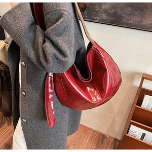 Detailed close-up of glossy red PU leather hobo bag with natural folds and wide strap