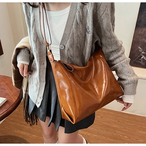 Détails de la texture du sac cabas en similicuir marron caramel brillant avec bandoulière