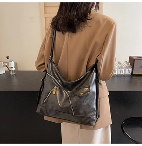 Close-up of a stylish black PU leather tote bag with gold zipper and pocket details