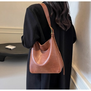 Detail view of caramel brown leather tote bag with adjustable strap and golden buckle