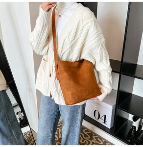 Brown suede crossbody bucket bag styled with a white sweater for an autumn casual look