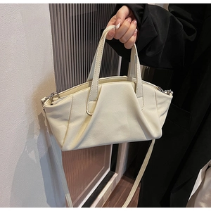 Detail of creamy white PU leather handbag with elegant pleats and silver hardware