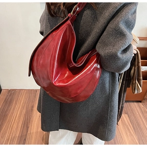 Detail of dark red glossy PU leather hobo bag styled with a grey coat for autumn