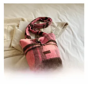 Detail showing the pink and brown plaid fluffy knit fabric and YAKIANM leather logo patch