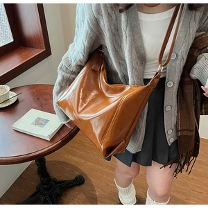 Vue détaillée du grand sac hobo en similicuir brillant caramel porté en bandoulière