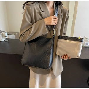 Detail of black textured shoulder bag and grey zip pouch with wide eyelet strap