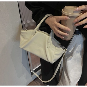 Detail of a minimalist cream PU leather crossbody bag with soft pleated texture and strap