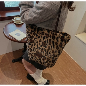 Detailed texture of leopard print faux fur tote bag with brown leather shoulder strap