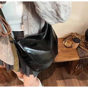 Detail of black Hobo bag with glossy finish and contrasting olive green wide strap