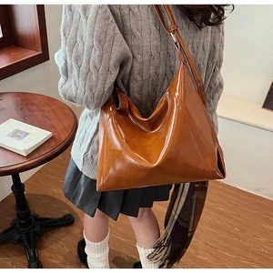 Détail du sac cabas en cuir verni caramel montrant la texture lisse et le gaufrage de la marque