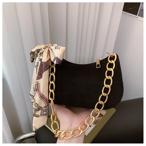 Detail of black suede crescent bag with chunky gold chain strap and silk scarf accessory