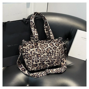 Fashionable leopard print tote bag with adjustable wide shoulder strap on a black sofa