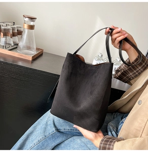 Detail of a minimalist black suede bucket bag with a contrasting brown leather interior