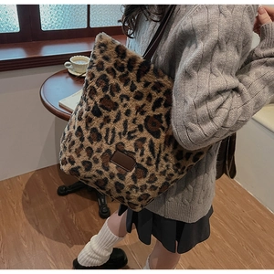 Detail of plush leopard print tote bag with brown leather strap and decorative logo patch