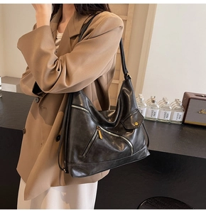 Detail of a black PU leather hobo bag with gold zippers and stylish side pocket decor