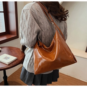 Détail d'un sac hobo en cuir PU marron caramel avec bandoulière réglable sur table en bois
