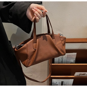 Detailed close-up of brown pleated PU leather handbag with dual handles and slender strap