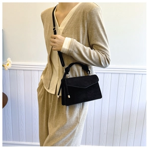 Detail of black matte envelope crossbody bag with a stylish knotted handle and strap