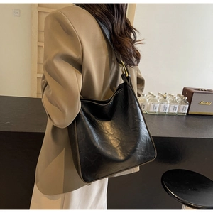 Close-up of a black vintage hobo bag with pleated texture and golden metal ring hardware