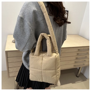 Close-up of beige quilted puffer tote bag on model shoulder with soft cloud texture