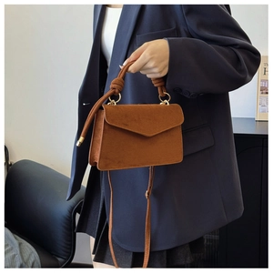 Detailed macro view of the brown suede envelope bag with knot handle and metal ring