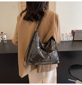 Detail of black PU leather hobo bag with multiple zippers shown worn on the shoulder
