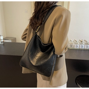 Close-up of black vintage tote bag with pleated leather texture and gold hardware